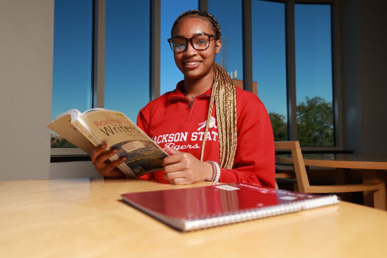 JSU student smiling while holding book